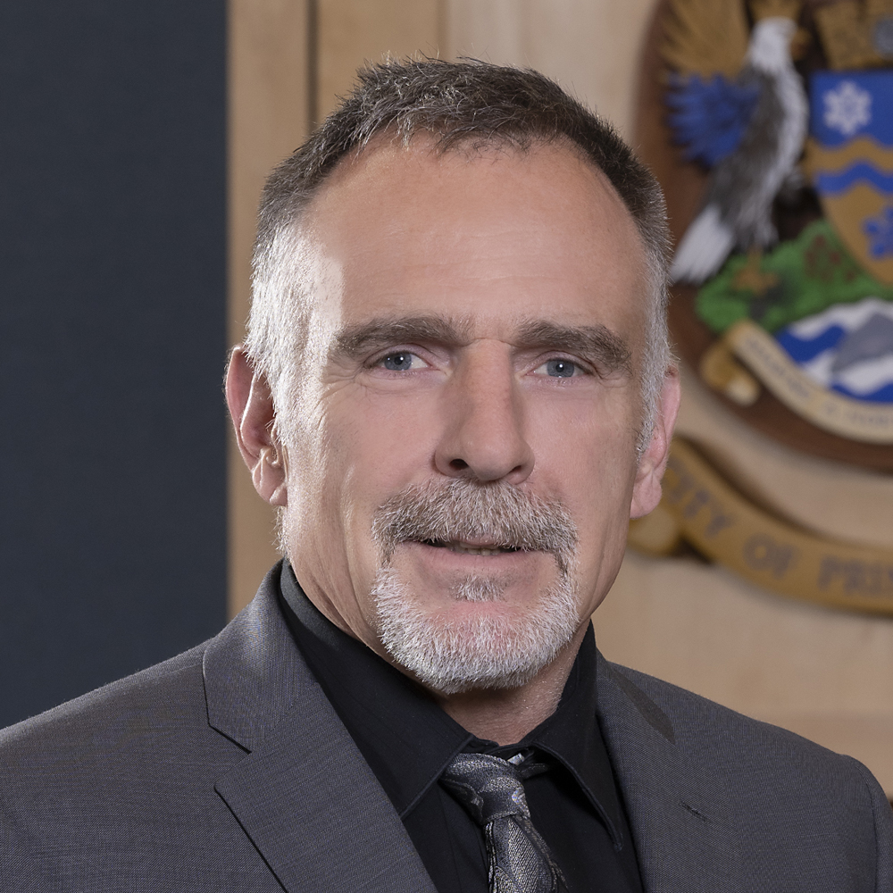 Headshot of Councillor Brian Skakun in council chambers, with City of Prince George crest partially visible in background.