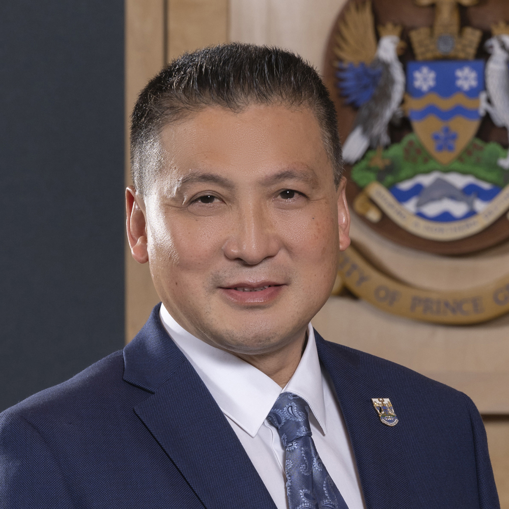 Headshot of Mayor Simon Yu in council chambers, with City of Prince George crest partially visible in background.