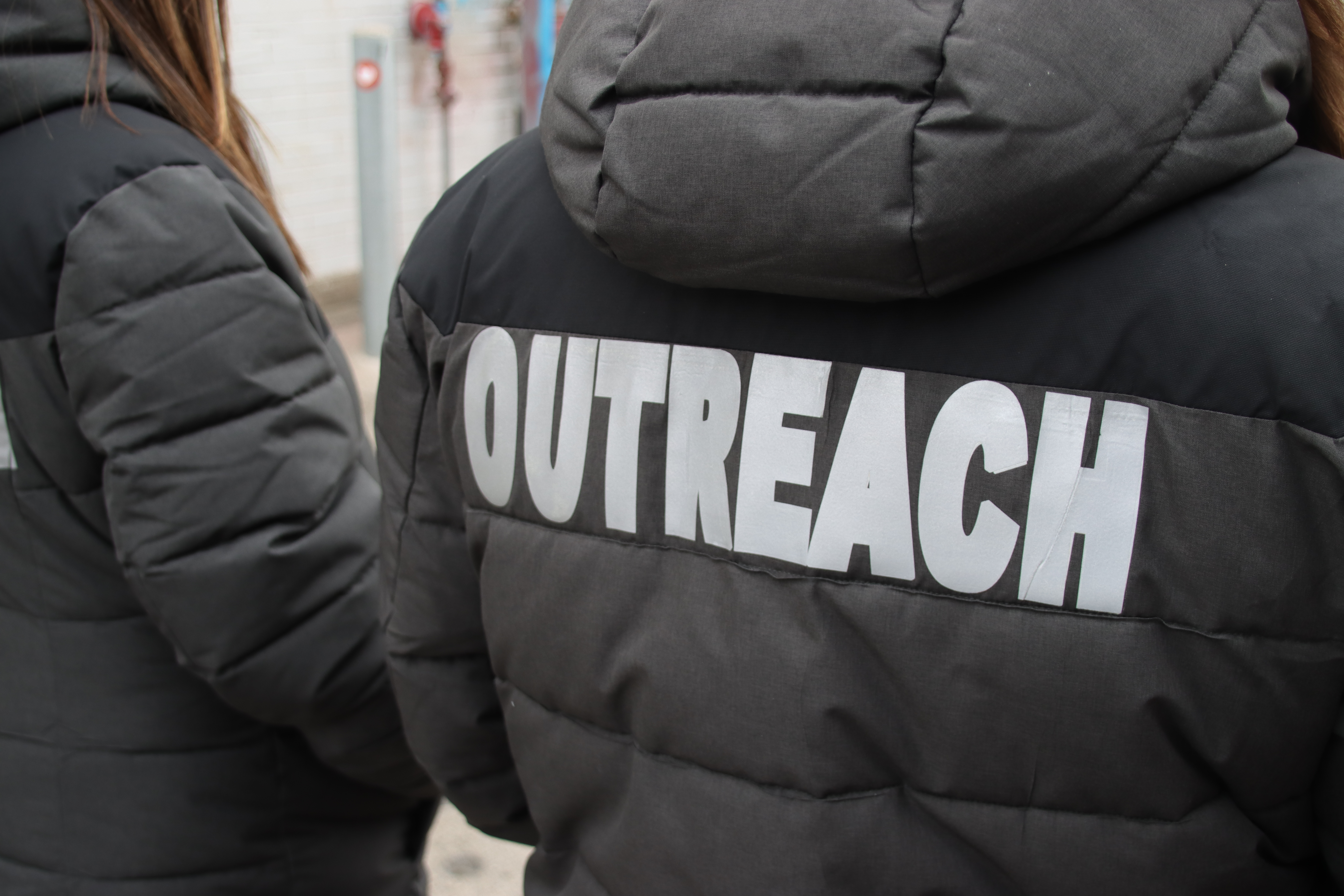 Outreach standing facing the distance in black outreach jackets