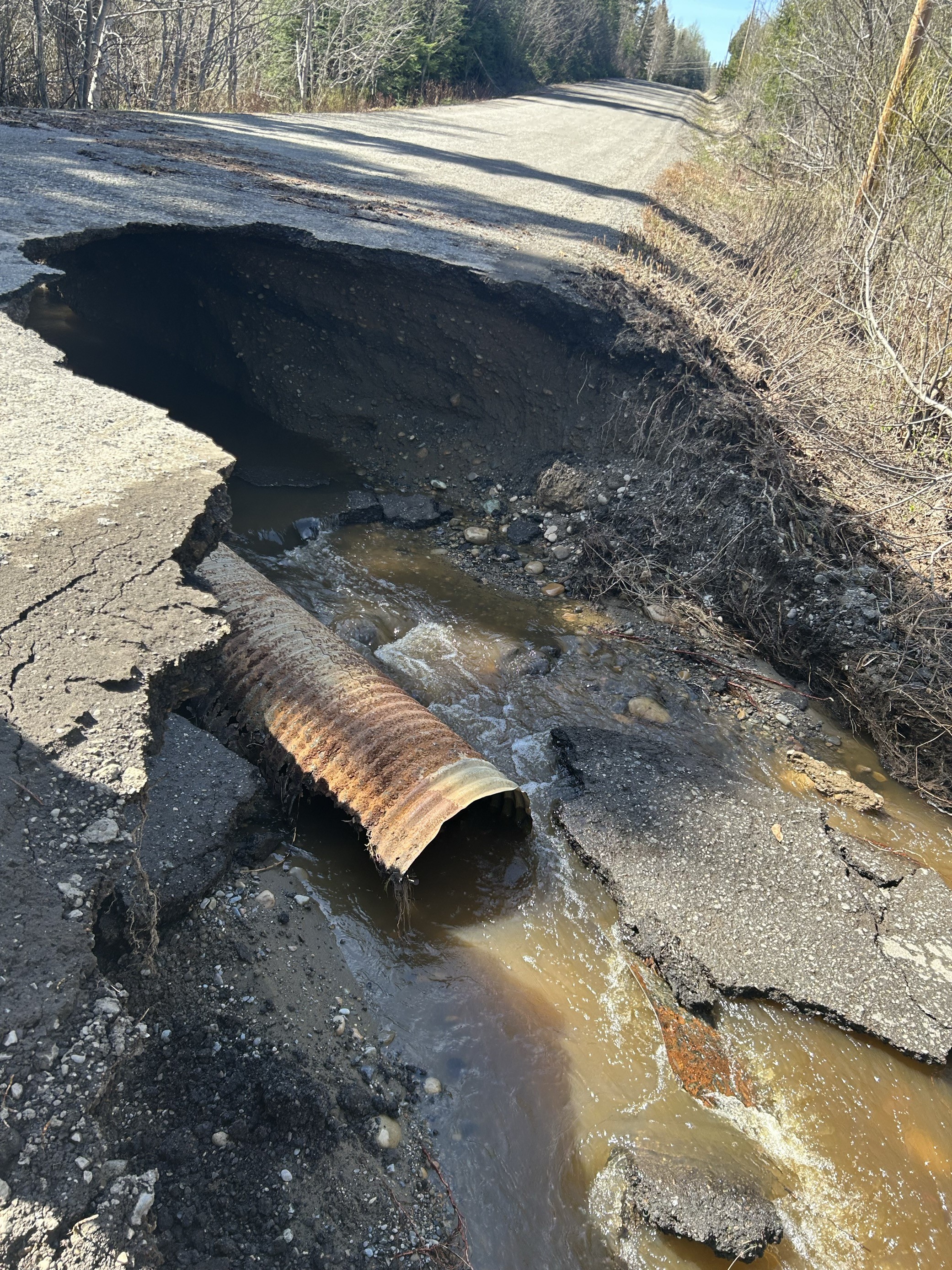 a photo showing a chunk of road missing with water underneath