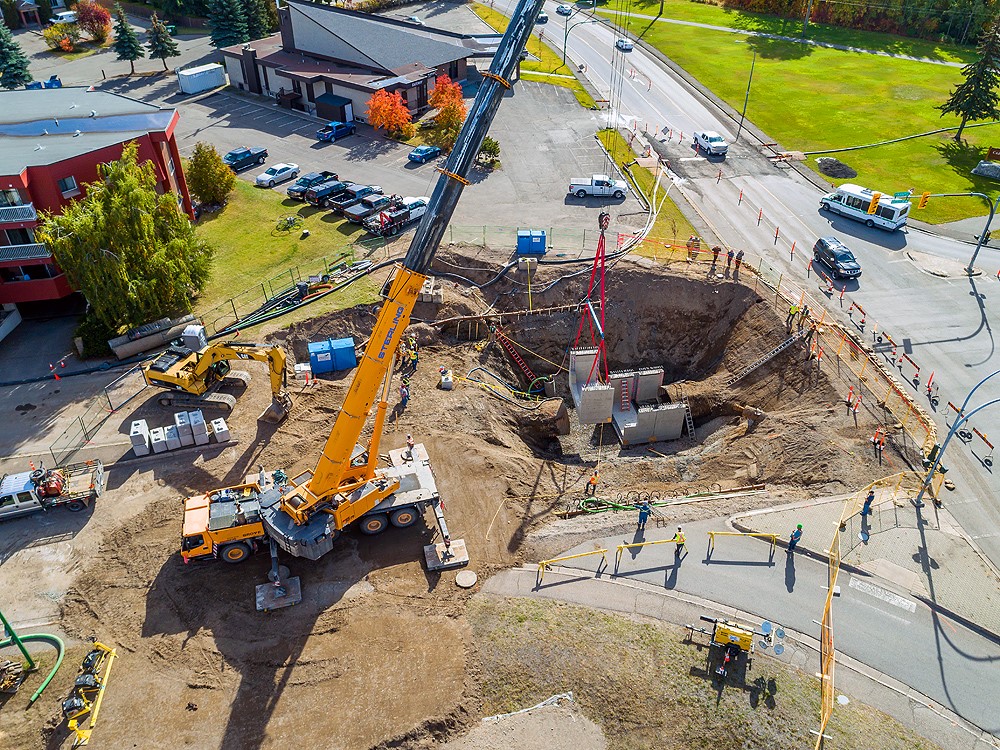 a photo showing a birds eye view of a sinkhole being repaired. There is a crane.