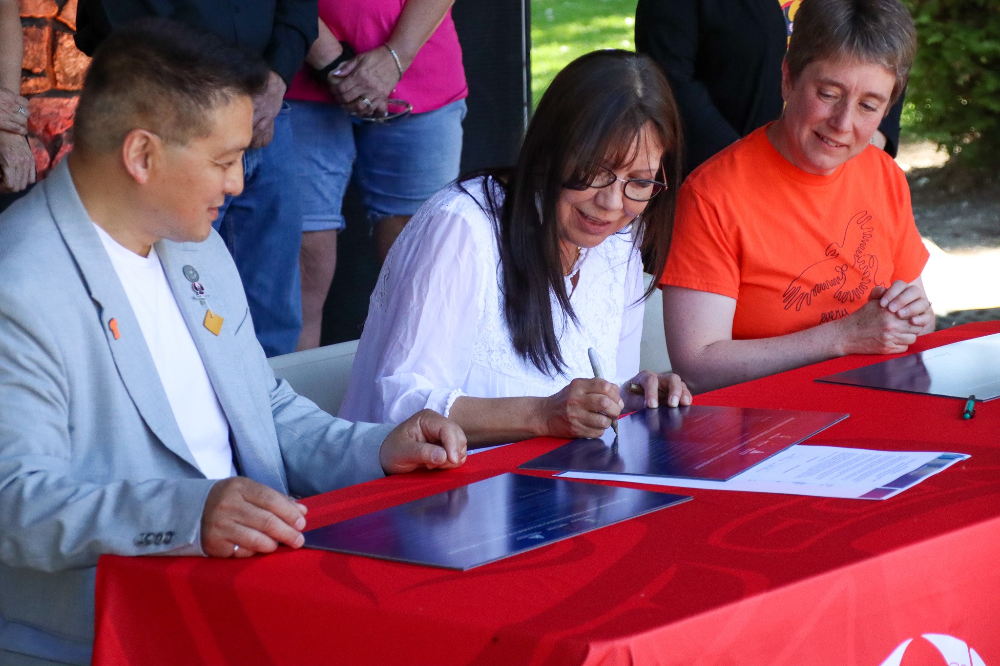 three people sitting at a desk signing a document