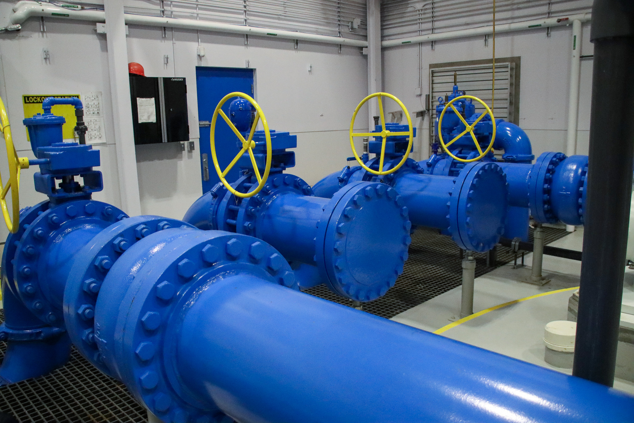 Large bright blue pipes with yellow valves inside a water reservoir