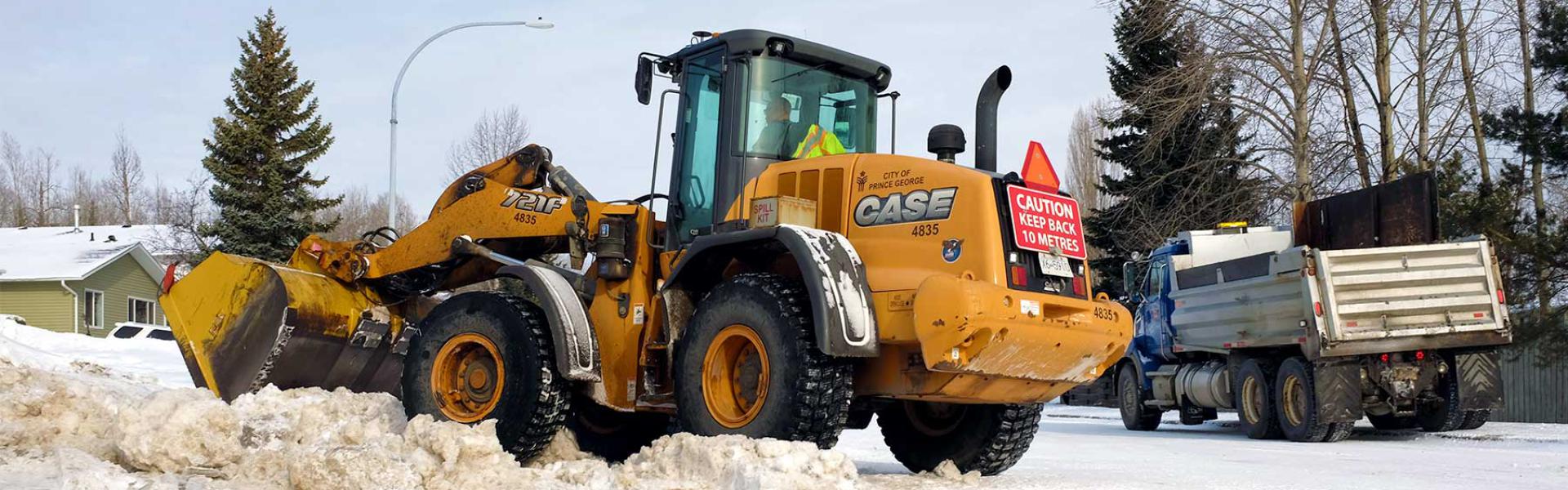 A snow plow clearing a residential street in winter.