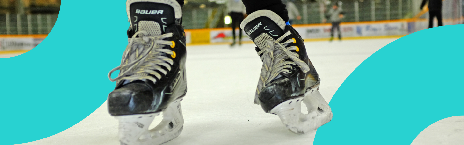A closeup of hockey skates on ice at an indoor arena