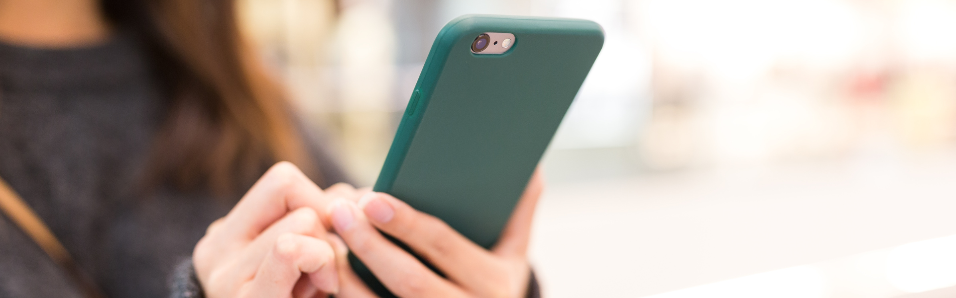 Closeup of a woman using a teal-coloured smartphone