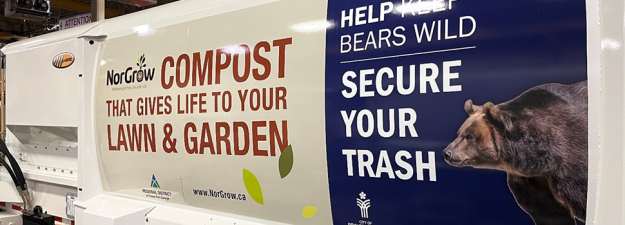a die shot of a garbage truck showing the sticker that has a picture of a bear and says SECURE YOUR TRASH