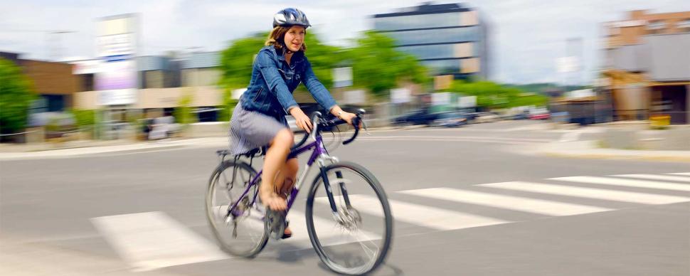 Woman in bike helmet cycling in downtown Prince George.