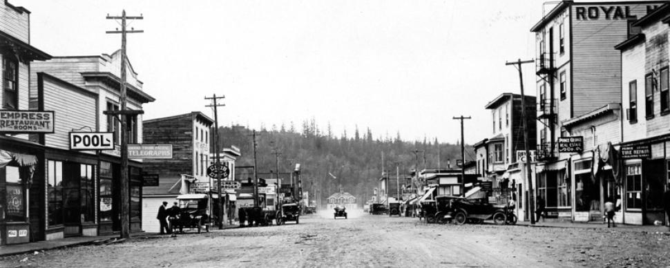 Historical photograph of George Street in 1920s Prince George with City Hall and Connaught Hill in the background.