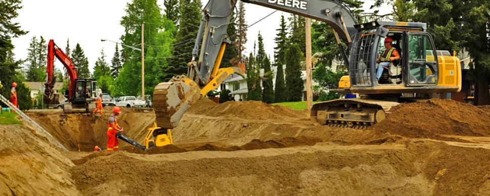 Heavy equipment digging large trench to install sewer pipes in a residential area
