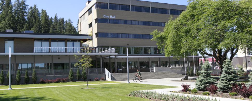Photo of City Hall with green grass, garden and trees in foreground.