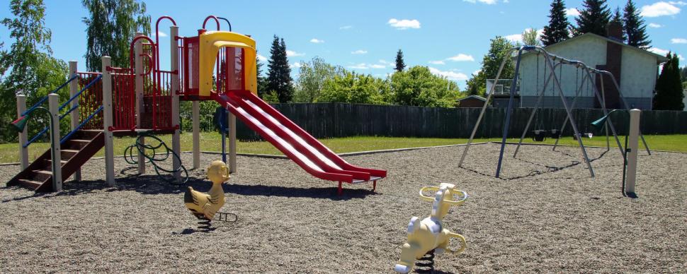 Playground equipment and swing sets. Sunny day with blue sky.