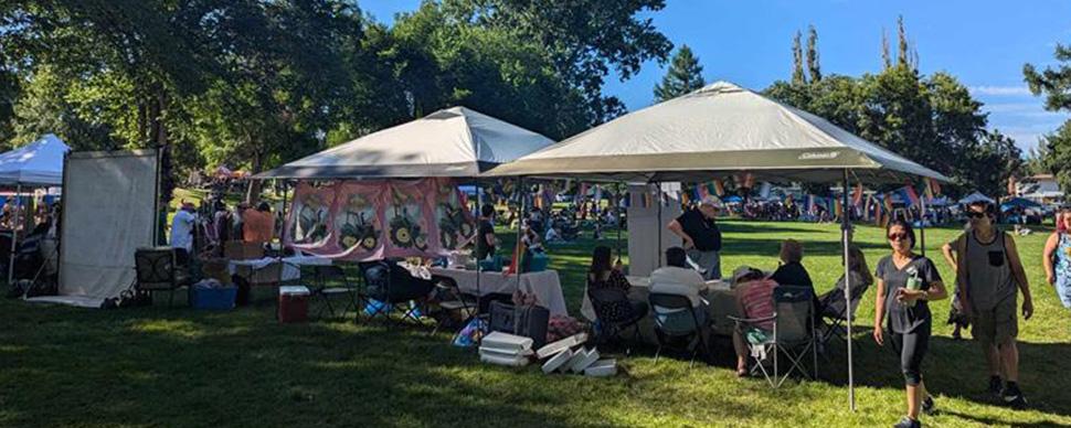 some marquee tents set up in the park with people sitting under them