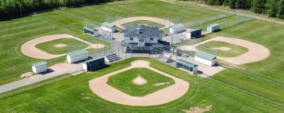 aerial view of four baseball diamonds surrounding a white clubhouse
