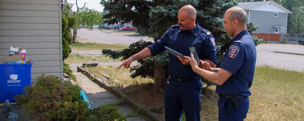 Two firefighters assessing a home for wildfire safety