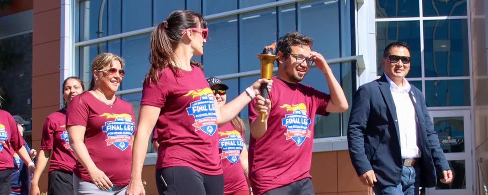 A group of athletes carrying the Special Olympics torch downtown