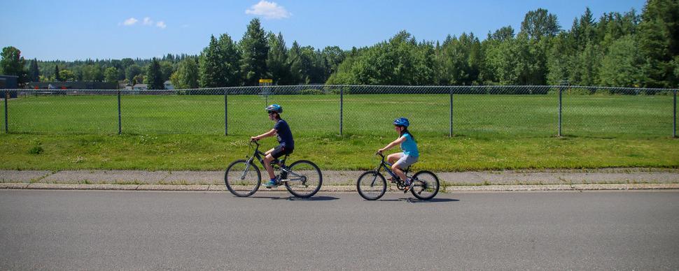 Two kids riding their bikes on a sunny summer day near Malaspina Elementary School