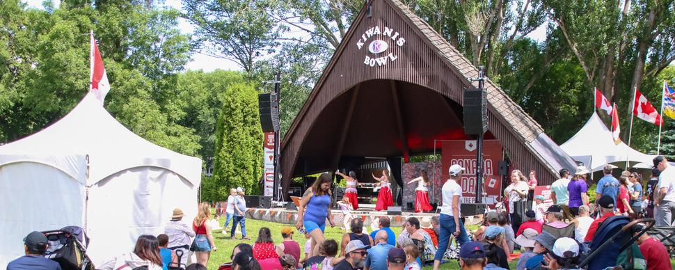 A group of dancers on stage in front of a crowd at an outdoor event