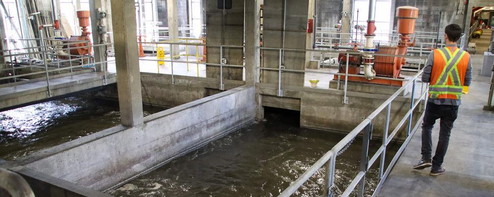 A person walks along a guard railing in a wastewater treatment facility