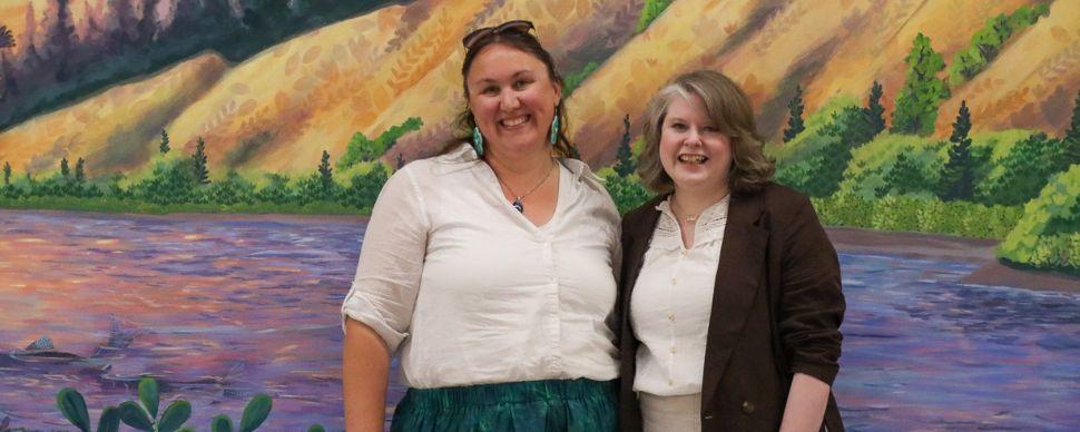Artists Kim Hayhurst and Erin Stagg smile in front of their mural at the Civic Centre 