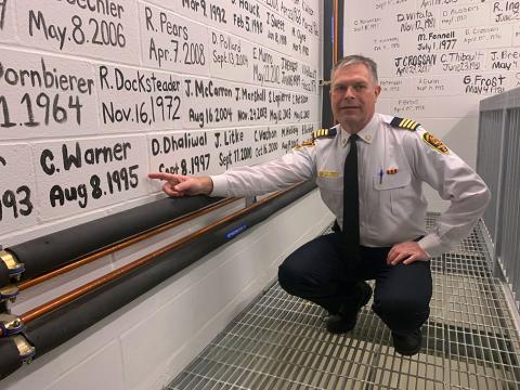 Fire Chief Cliff Warner points to his name and start date (August 8, 1995) painted on the wall at the new Fire Hall #1