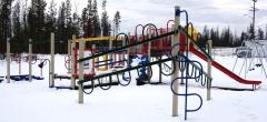 Playground with slide and climbing structures surrounded by snow